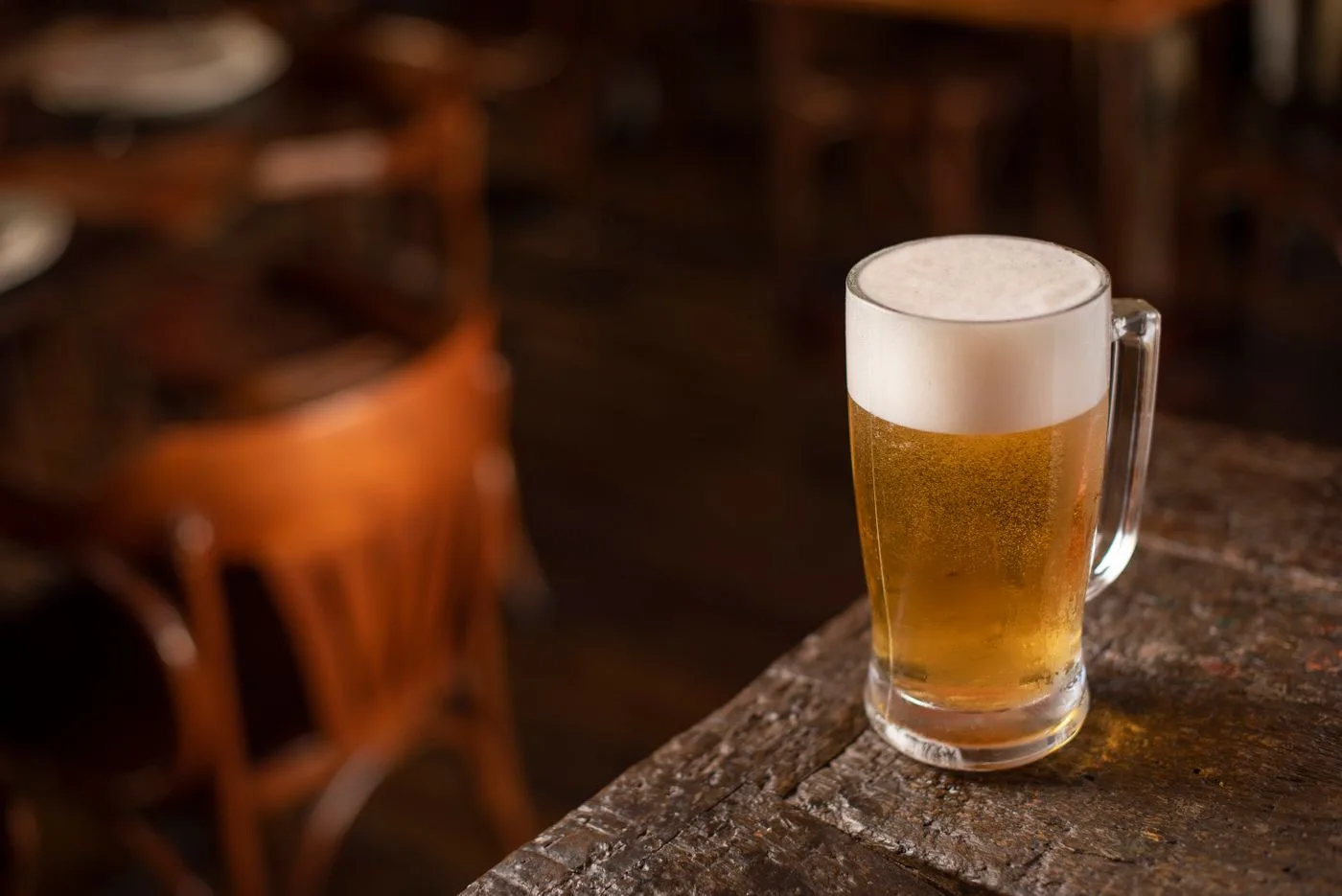 Symbolfoto: heller Bierkrug mit Schaumkrone auf einem Holztisch