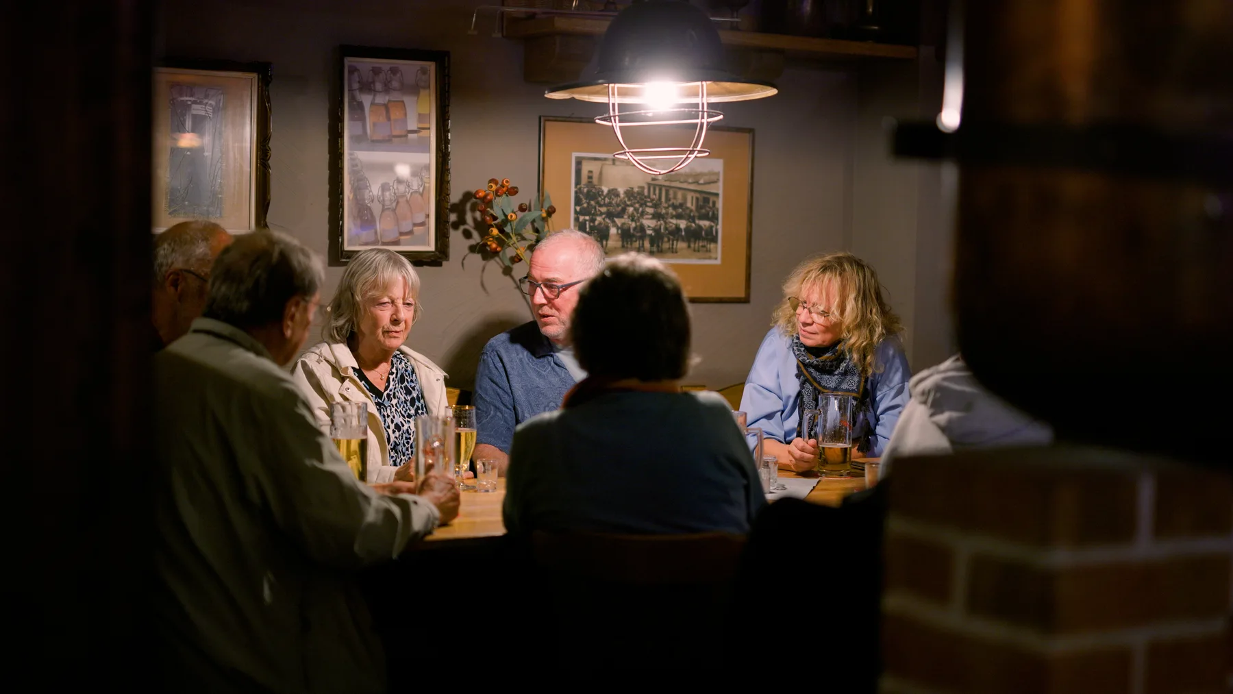Gäste verbringen einen gemeinsamen Abend am Holztisch im Brauhaus