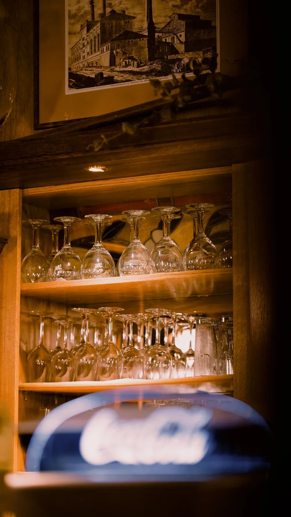 Gläser im warm beleuchteten Holzregal der Brauhausbar